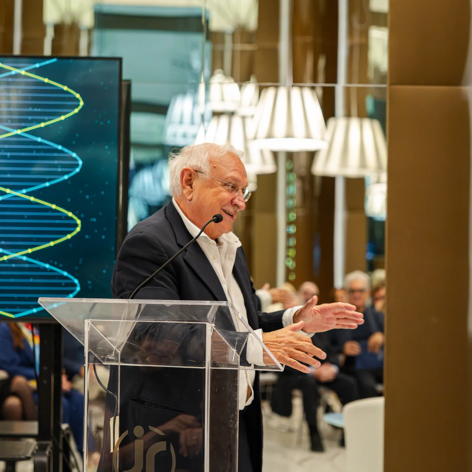 Al leggio, con la doppia elica del DNA alle spalle